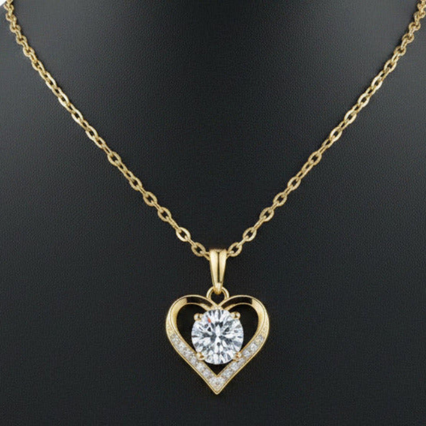 Gold heart-shaped necklace with a clear gemstone on a white background