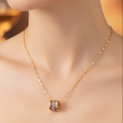 Gold necklace with a purple gemstone pendant on a neck