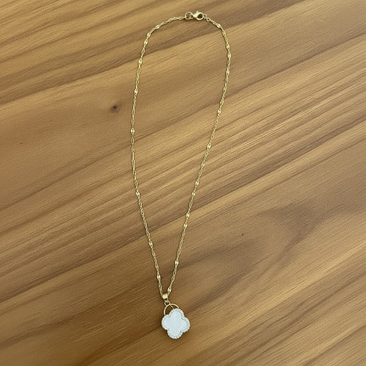 Gold necklace with a spinning pendant on a textured surface