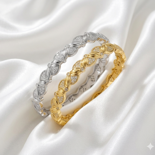 Two gold and silver bracelets on a white satin background