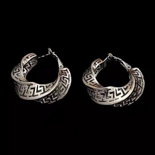 Pair of silver hoop earrings with intricate designs on a black background