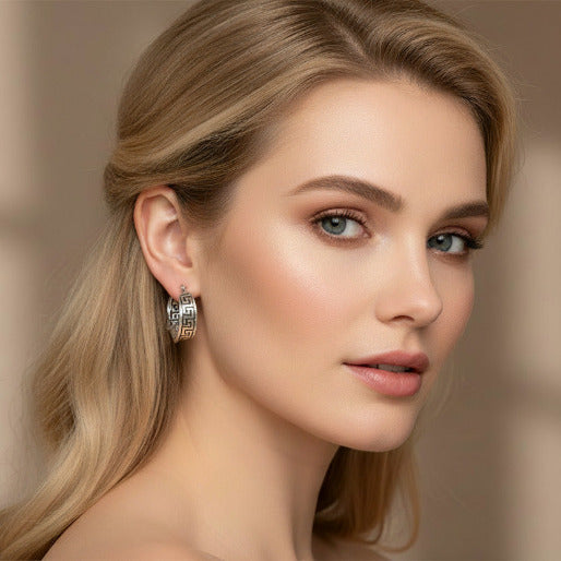 Pair of silver hoop earrings with intricate designs on a blond girl