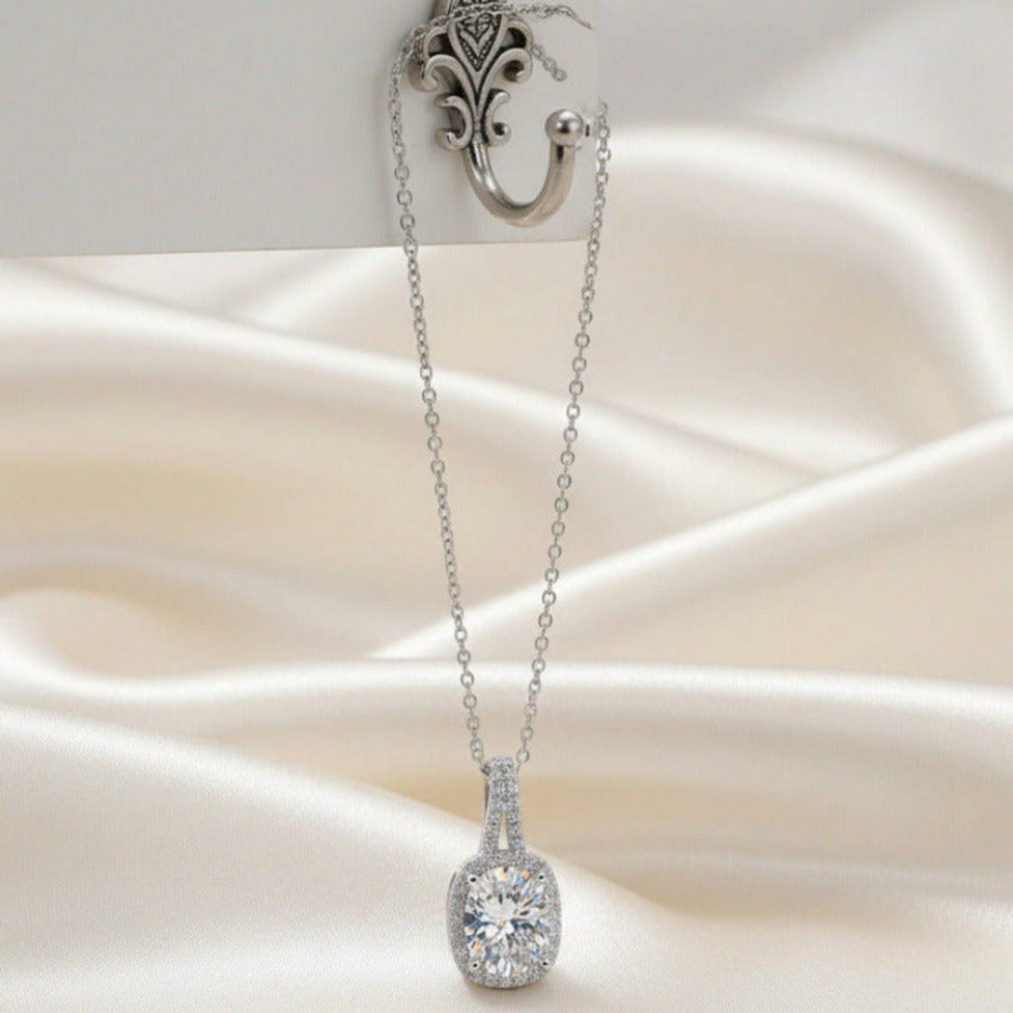 Silver necklace with a clear gemstone pendant on a white fabric background