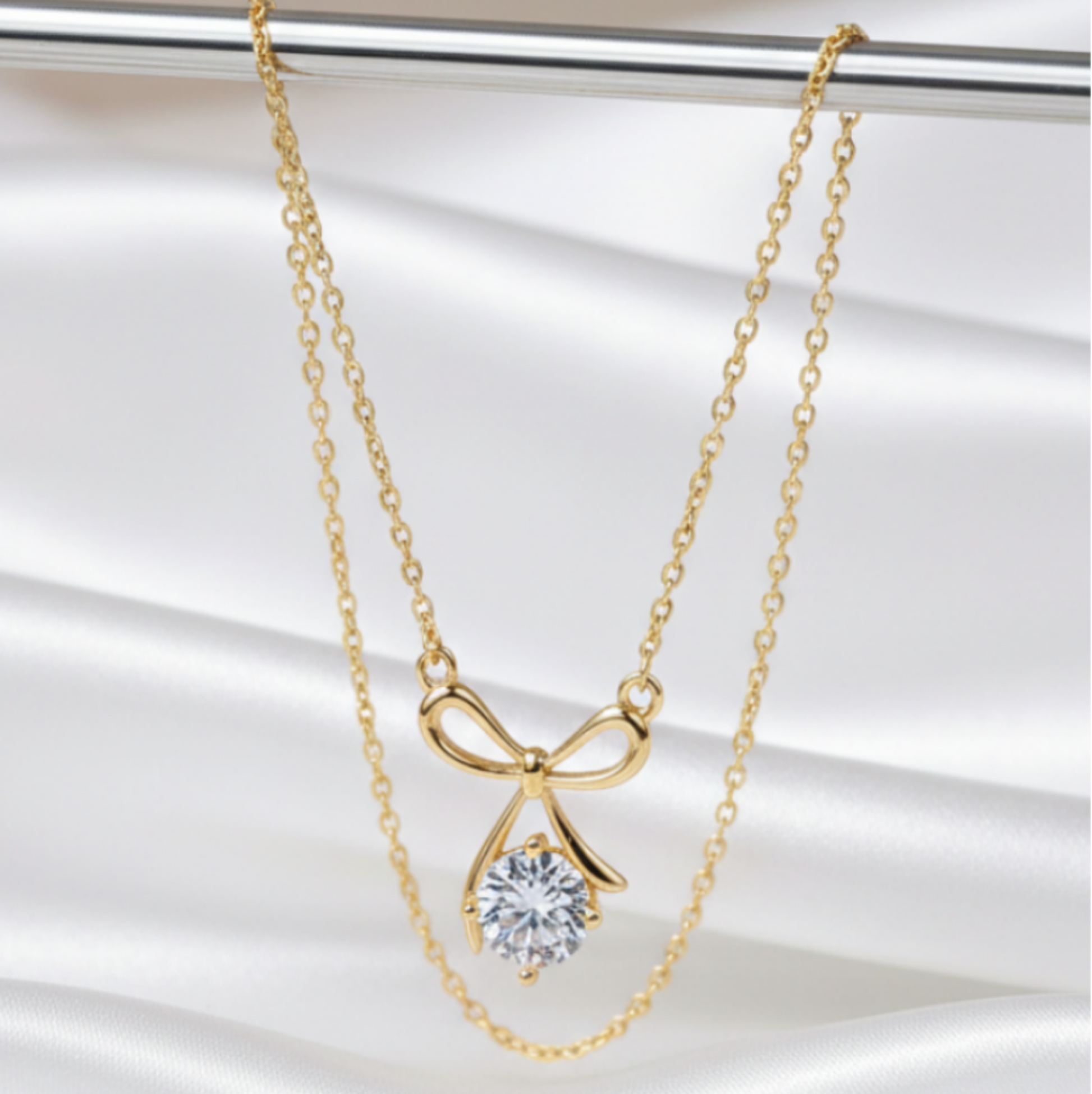 Gold bow-shaped necklace with a clear gemstone pendant on a white background