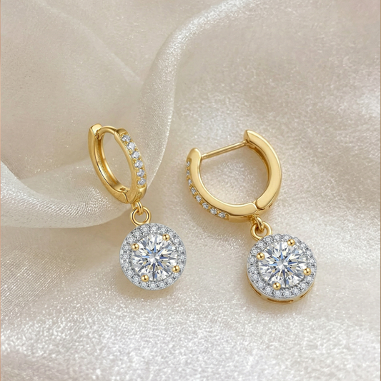 Gold hoop earrings with round diamond-like moissanite stones on a soft fabric background