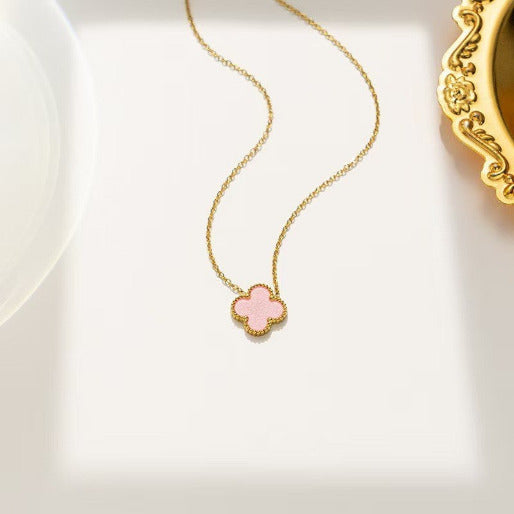 Gold necklace with a pink clover-shaped pendant on a white background