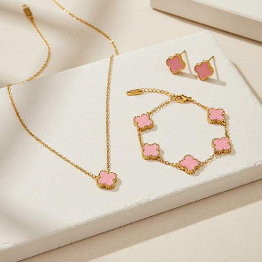 Jewelry set with pink clover-shaped pendants including necklace, bracelet, and earrings on a white background.