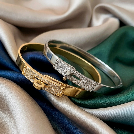 Two gold and silver bracelets on a satin fabric background