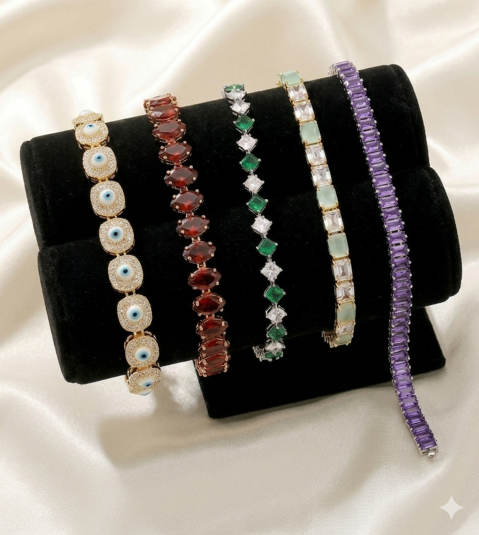 Set of five tennis bracelets with various gemstones on a black stand against a white background