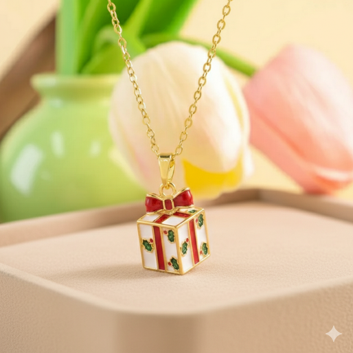 Gold necklace with a gift box pendant. The pendant is crafted with a white base, decorated with vibrant red enamel striping resembling ribbons, and adorned with small green holly leaves and red berries. A delicate red bow sits atop the gift box, completing its festive appearance. The pendant is connected to a fine, gold-toned chain, making it a perfect accessory for holiday celebration.