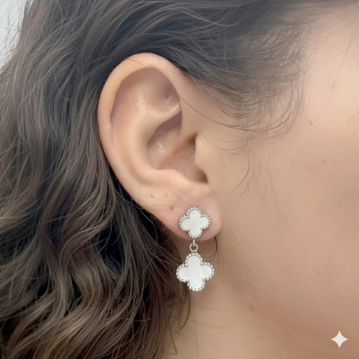 Close-up of an ear wearing a silver earring with a white double clover design.