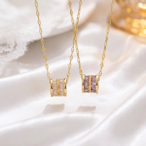 Gold necklaces with purple and clear gemstones on a white surface