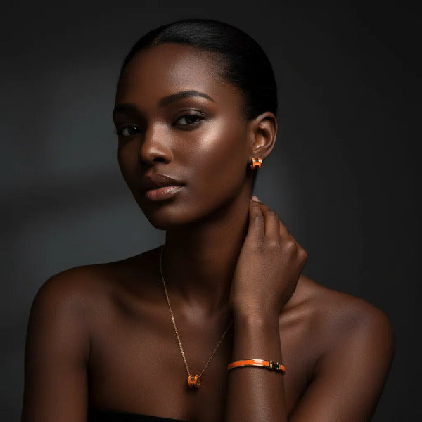 Stunning three-piece jewelry set featuring a gold tone metal and vibrant range enamel, all adorned with a distinctive 'H' motif. The pieces are designed for visual harmony, intended to be worn together or individually to add a touch of sophisticated flair.