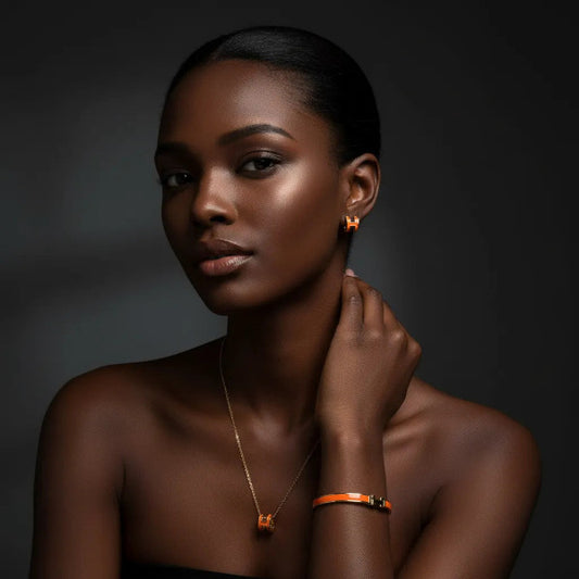 Stunning three-piece jewelry set featuring a gold tone metal and vibrant range enamel, all adorned with a distinctive 'H' motif. The pieces are designed for visual harmony, intended to be worn together or individually to add a touch of sophisticated flair.