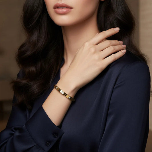 Woman wearing a gold bangle bracelet on her wrist with embedded gemstones, creating a seamless and snag-free profile.