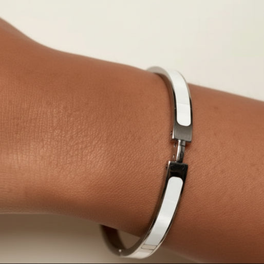 Silver finished H bracelet with a band inlaid white enamel. Gold plated titanium steel.