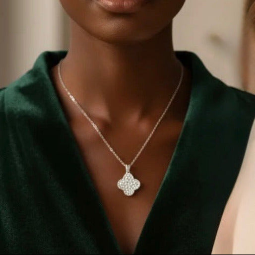 Silver tone necklace featuring a four leaf clover encrusted with numerous small, clear, brilliant set in a pave style, giving an sparkling appearance.