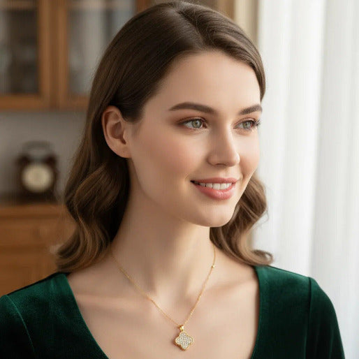Woman wearing a gold necklace with a white clover pendant with multiple sparkling accent stones in it.