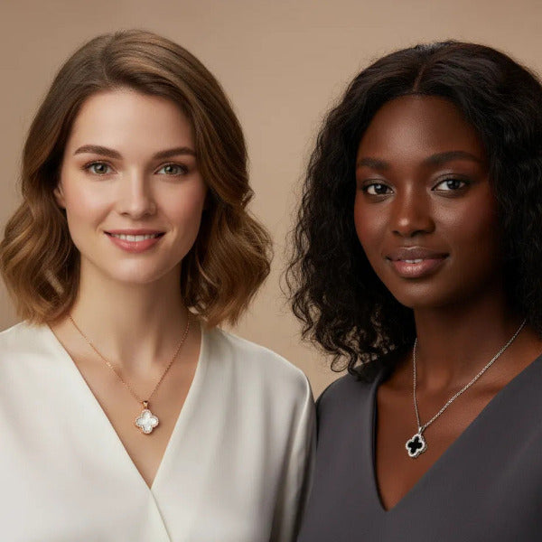 Two iconic necklaces, notable for their distinctive four-leaf clover motif. On the left, a pendant crafted from 18K yellow gold plating titanium steel features a luminous white inlay, suspended on a delicate gold chain. On the right, a second  pendant displays a striking black inlay, set within a 18K white gold plated titanium steel frame  and paired with a matching chain.