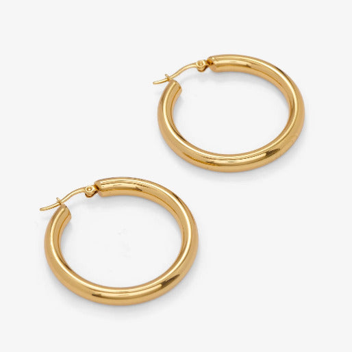 These earrings feature a substantial, medium thick tube design, suggesting durability and comfortable feel. They are crafted from 18K yellow gold over stainless steel.