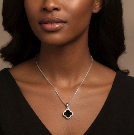 Woman wearing a necklace with a black clover pendant. 
