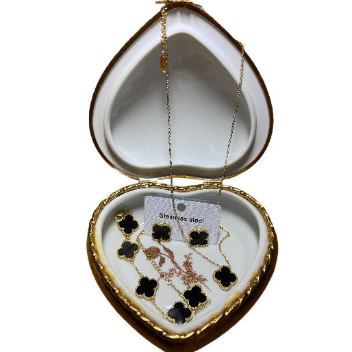 Black clover gold jewelry set showed in a heart shaped jewelry box.