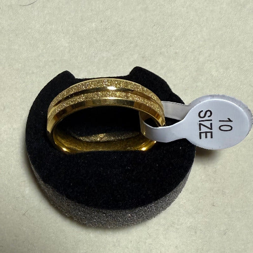Gold ring on a black cushion with a size tag indicating '10'.  The frosted or granular texture across the surface of the two parallel bands provides a subtle shimmer and a contemporary matte finish, contrasting with the typical highly polished rings.