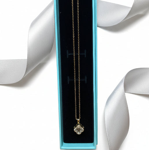 Gold Necklace with a clover pendant showcasing a prominent central stone, surrounded by smaller, sparkling accent stones.  This jewel catches the light so effectively that makes the piece stands out even on a simple chain. 