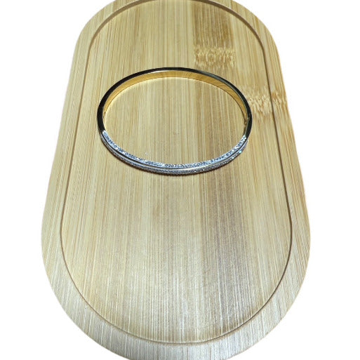 This elegant bangle bracelet features a sophisticated 'halfway' design, with three parallel rows of zircons meticulously set in a pave style across its upper surface.