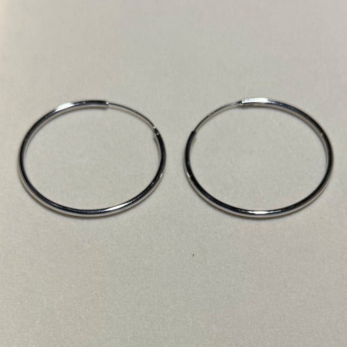Classical earrings featuring a simple, continuous circular design, designed to be worn through pierced ears. These earrings are a versatile staple for any jewelry collection.