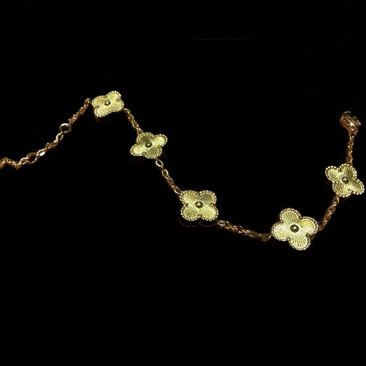 Gold bracelet with clover-shaped charms on a black background