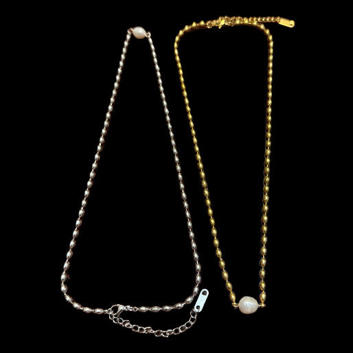Gold and silver necklaces with a pearl , contrasting on a black background