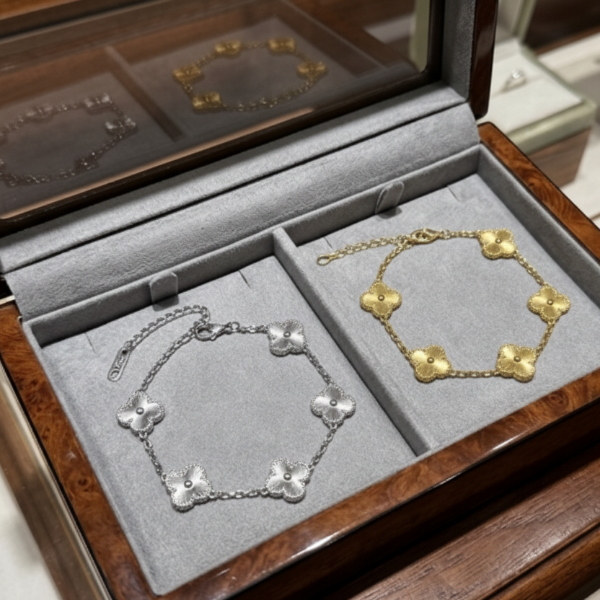 Jewelry box showing silver and gold bracelets with clover motifs, on a wooden surface
