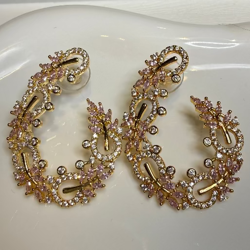 Gold and pink hoop earrings on a white dish