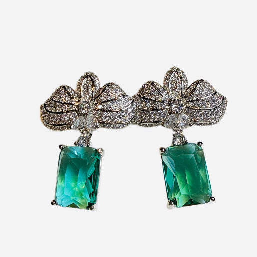 Pair of earrings with green gemstones and silver accents on a white background