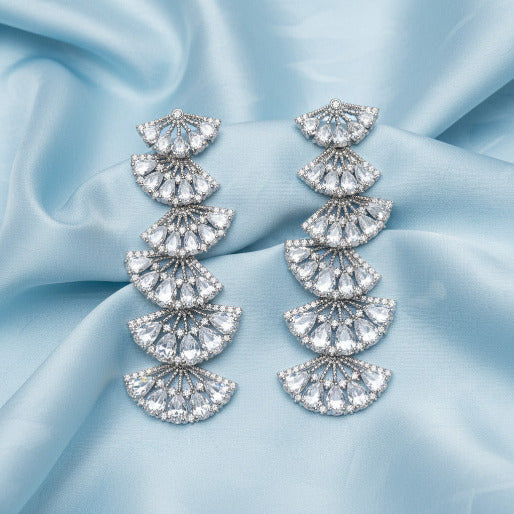 Pair of silver dangle zircon diamond earrings on a blue background
