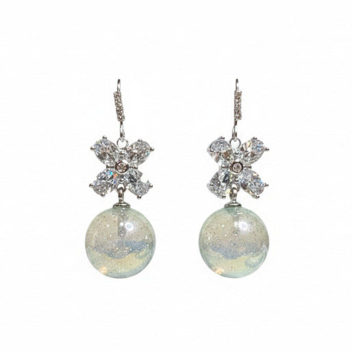 Pair of silver earrings with floral tops and round dangling light blue elements on a white background.