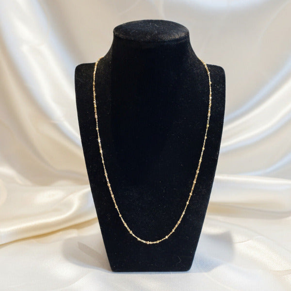 Gold beaded necklace on a black velvet mannequin bust
