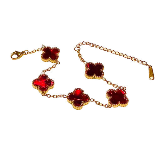Bracelet with deep red clover charms on a white plate