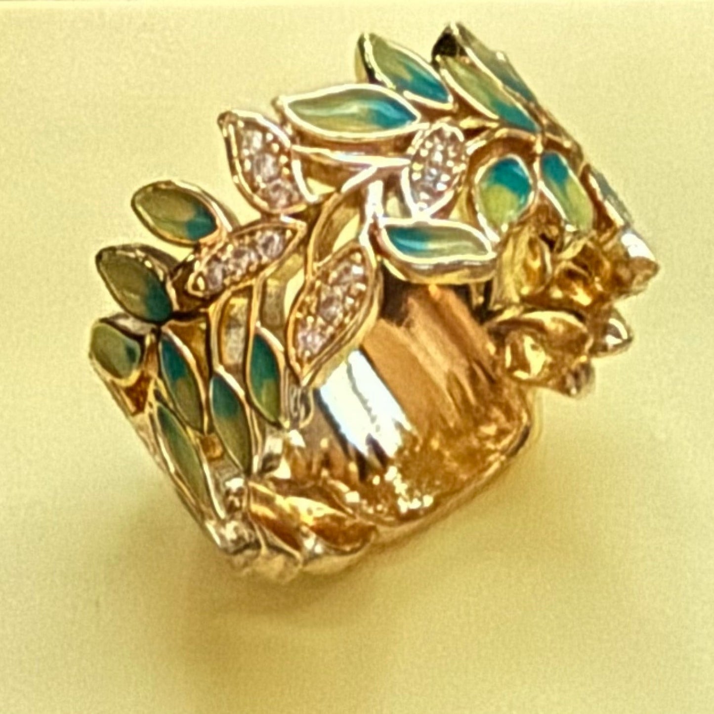 Gold ring with green enamel and diamond like crystals on a yellow background
