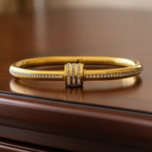 Gold bracelet with a decorative barrel with zircons on it.