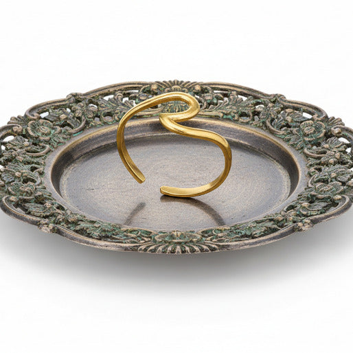 Gold open ocean wave ring on a antique jewelry plate. The continuous flow of the wave creates a sense of effortless elegance