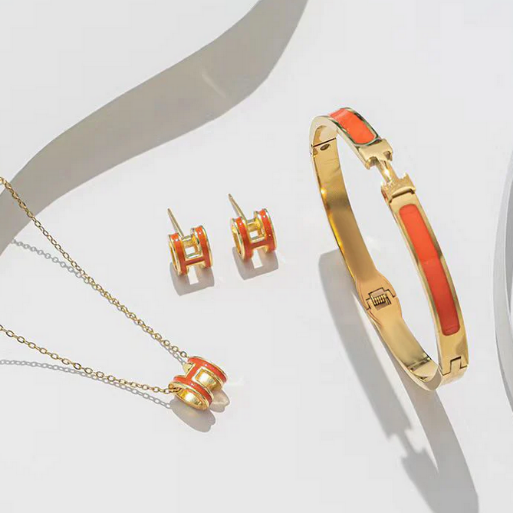 This set includes a hinged bangle bracelet, a pair of matching stud earrings, and a delicate necklace with a pendant, This collection has a iconic design making it a statement accessory for any occasion. 