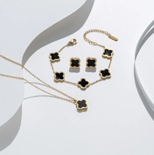Details of the clover jewelry set in gold and black, showing necklace, bracelet and earrings.