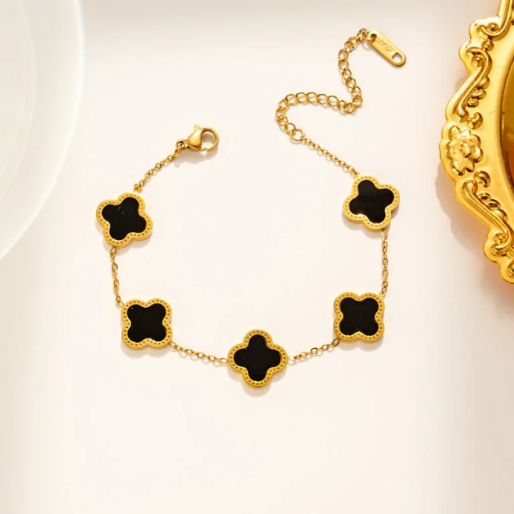 Gold bracelet with black clover-shaped motifs. These motifs are linked together by a fine golden chain and the bracelet includes an extender for an adjustable fit. designed to adorn the wrist with a touch of elegance and classic style.