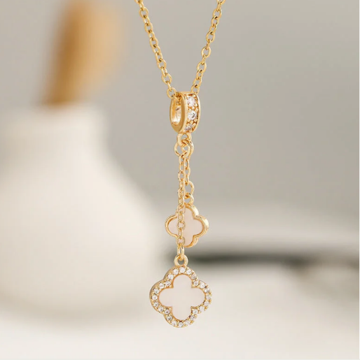 Detail of gold necklace with white double clover pendant.