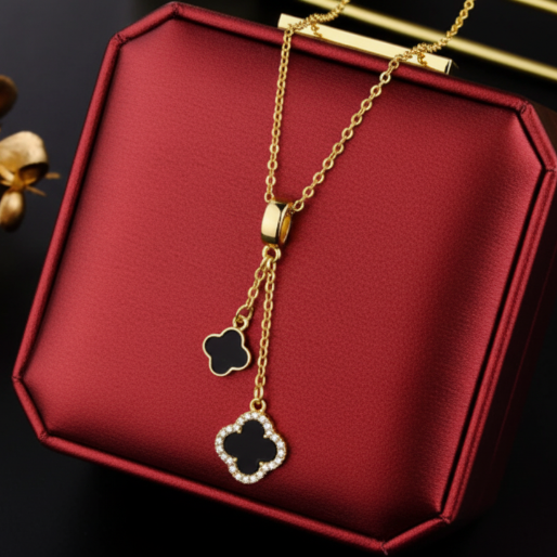 Detail of gold necklace with black double clover pendant.
