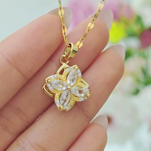 The pendant is adorned with four marquise cut clear stones that resemble petals, set within a matching gold toned frame.  This creates a vibrant sparkle, and provides a rich contrast, highlighting the intricate structure of the piece.