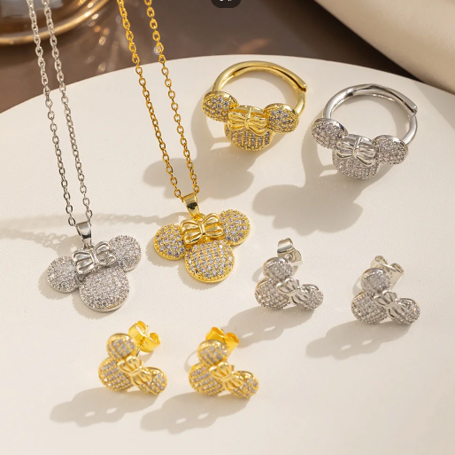 This imagine displays the versatility of this jewelry set by featuring both the silver tone and gold tone options simultaneously. This highlights how the same playful design can achieve different aesthetic: the silver tone offering a classic, sleek look while the gold tone exudates warm and luxury.