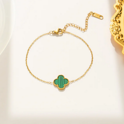 Gold bracelet with a green clover-shaped charm. These design is often chosen for its classic design, believed to symbolize luck, and are popular as everyday wear or for special occasions.
